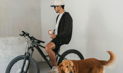 a man sitting on a bike next to a dog